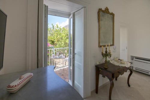 Camera Bouganvillea al Relais Palazzo Cacace a Meta di Sorrento con porte aperte sulla vista giardino, arredi eleganti e
