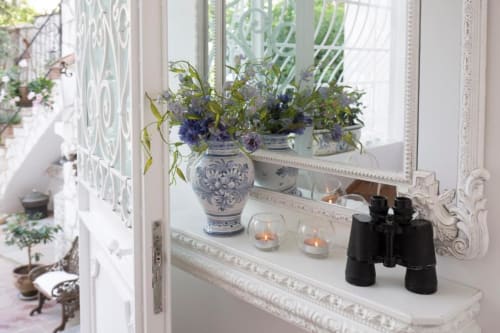 Elegante composizione sul davanzale di Relais Palazzo Cacace con vasi di ceramica blu, fiori, candele e binocoli con vista
