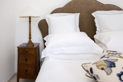 Camera Deluxe Anthea presso Relais Palazzo Cacace: elegante letto matrimoniale con biancheria bianca, testata imbottita e
