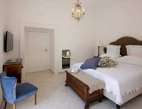 Elegante camera matrimoniale Anthea Deluxe al Relais Palazzo Cacace, Meta di Sorrento, con letto in legno e biancheria bianca