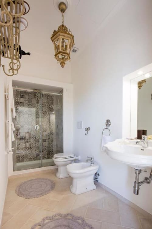 Elegante bagno della Anthea Deluxe Room al Relais Palazzo Cacace di Meta di Sorrento, con piastrelle in marmo e finiture in ottone