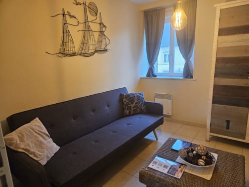 Séjour cosy de l'appartement Les Ebihens à Saint-Benoît-des-Ondes avec canapé foncé, décoration voilier et mobilier contemporain