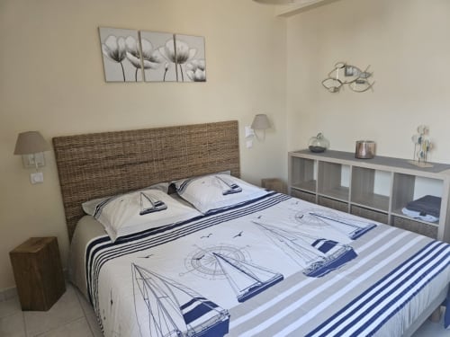 Chambre aux motifs nautiques avec tête de lit tissée, parure de lit voilier et coussins rayés au Clos De La Côte D'émeraude
