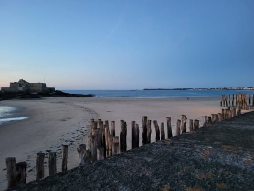 Vue côtière de Saint-Benoît-des-Ondes avec ses pieux en bois, fort et ciel bleu dégagé