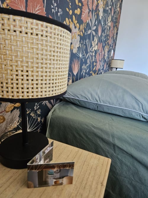 Coin cosy de la chambre du gîte Le Banc des Hermelles à Saint-Benoît-des-Ondes avec tête de lit fleurie bleue, lampe et gris