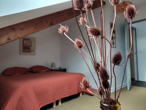 Chambre douillette au gîte Le Clos De La Côte D'emeraude avec parure de lit corail, poutre en bois et fleurs séchées en vase