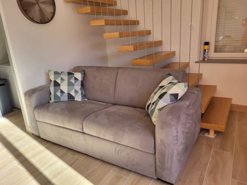 Canapé gris rembourré avec coussins à motifs dans un salon moderne de style cottage au Clos De La Côte D'émeraude, Saint-Benoît-des-Ondes