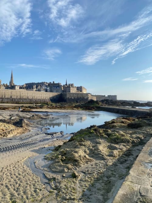 La cité médiévale fortifiée de Saint-Benoît-des-Ondes domine une plage rocheuse avec des bassins de marée à marée basse
