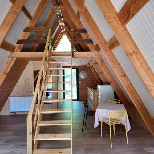 Intérieur du chalet en A de La Font Vineuse Spa Hotel avec poutres en bois, échelle, coin repas et vue sur les montagnes