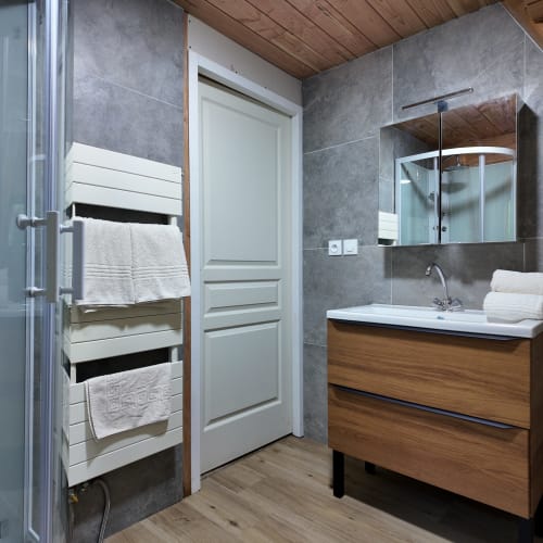 Salle de bains moderne à la Spa Hotel La Font Vineuse avec carrelage gris, meuble-lavabo en bois, porte-serviettes chauffant et douche