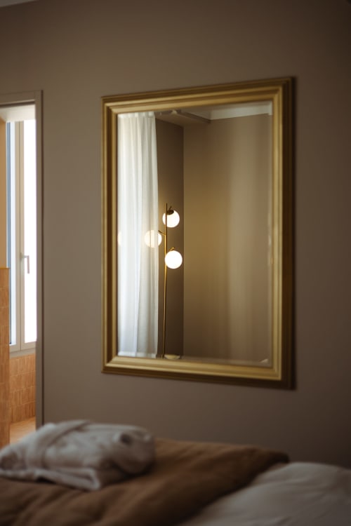 Miroir encadré doré dans la Chambre Joséphine à L'Ode à Pierre, gîte Dax, reflétant une lampe moderne en laiton et l'intérieur de la chambre