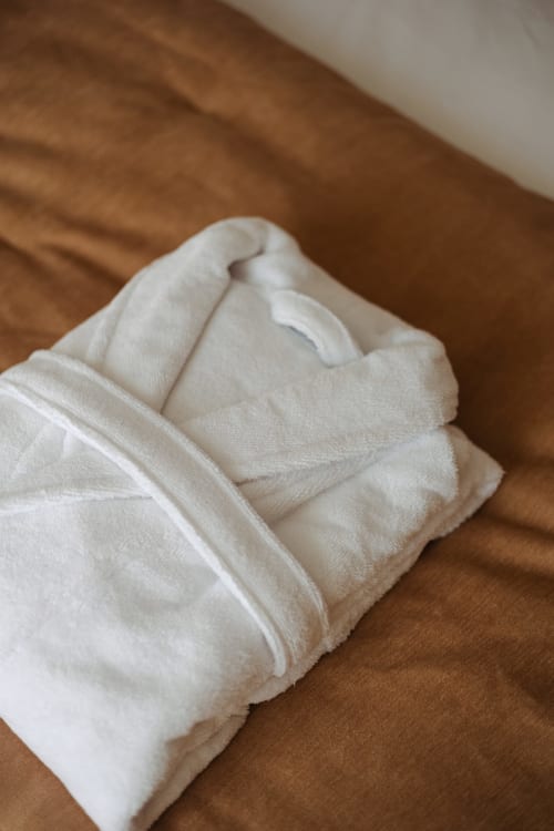 Serviette blanche roulée avec soin sur la literie marron à L'Ode à Pierre, Dax