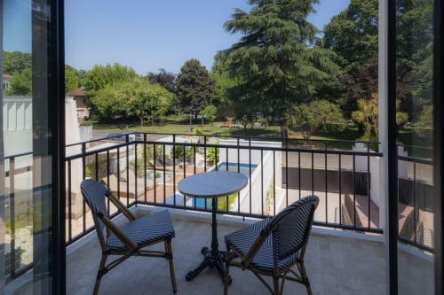 Coin salon sur le balcon de la chambre Coco à L'Ode à Pierre B&B à Dax, vue sur la piscine et le jardin