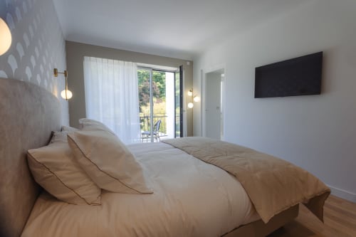 Chambre lumineuse avec lit, télévision et balcon à la maison d'hôtes L'Ode à Pierre à Dax