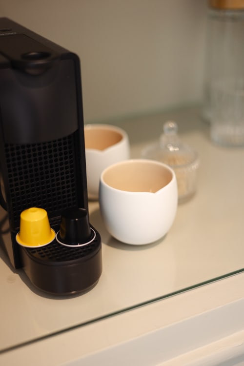 Machine Nespresso noire avec capsule jaune et tasses blanches à la boutique-hôtel L'Ode à Pierre à Dax