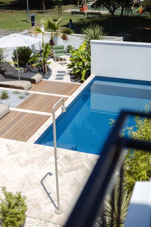 Vue de la piscine L'Ode à Pierre à Dax, France - bassin bleu avec terrasse en bois et plantes tropicales