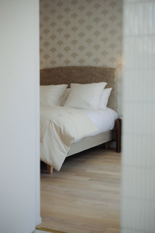 Chambre de la maison d'hôtes L'Ode à Pierre à Dax avec papier peint beige à motifs et literie blanche