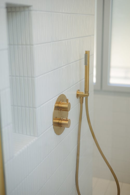 Robinetterie dorée et commandes sur carrelage blanc dans la salle de bain Chambre Coco à L'Ode à Pierre, Dax