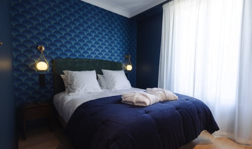 Chambre moderne à L'Ode à Pierre B&B à Dax avec murs à motifs bleus, tête de lit foncée et suspensions en laiton