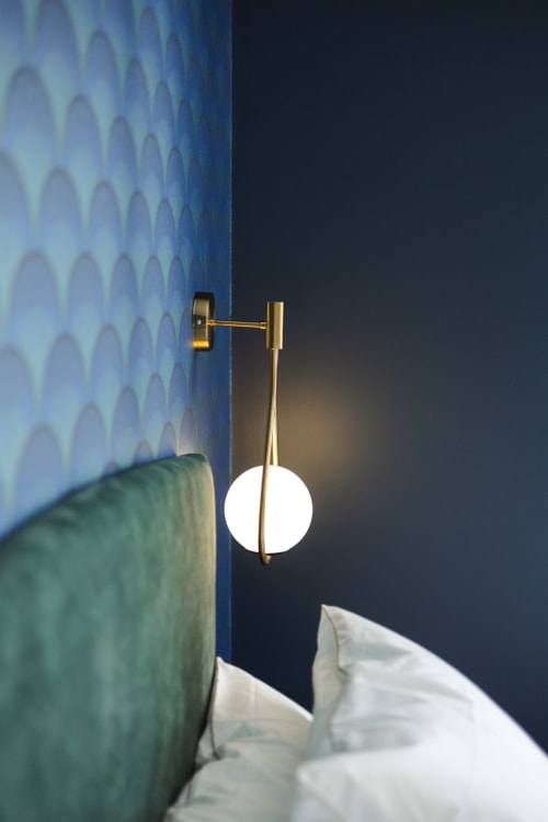 Applique murale en laiton moderne avec sphère lumineuse au-dessus du lit dans la Chambre Mistinguett de L'Ode à Pierre, Dax