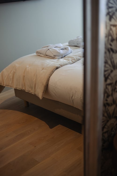 Literie crème avec serviettes pliées sur le lit de l'hôtel-boutique L'Ode à Pierre à Dax, France