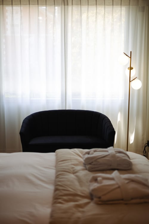 Chambre Gatsby à L'Ode à Pierre B&B à Dax avec canapé incurvé anthracite, lampadaire en laiton et voilages délicats