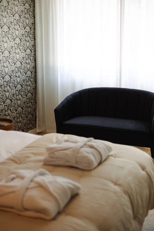 Chambre Gatsby à L'Ode à Pierre BnB à Dax avec lit crème, canapé noir et papier peint botanique
