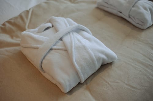 Peignoirs spa blancs avec ceintures sur le lit de la Chambre Gatsby à L'Ode à Pierre, boutique hôtel à Dax