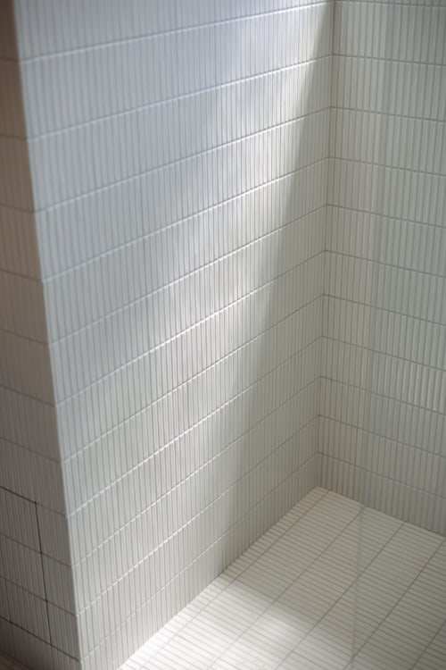 Coin de salle de bain aux carreaux blancs modernes avec motif géométrique au sol, Chambre Gatsby, hôtel boutique L'Ode à Pierre à Dax