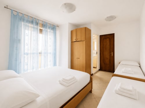 Camera doppia nell'Appartamento Timavo dell'hotel Anthea a Lignano Sabbiadoro con armadi in legno e vista sul giardino