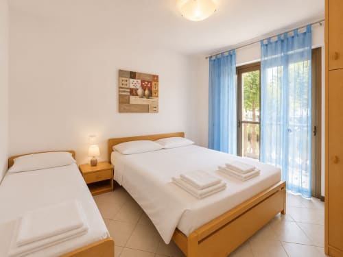 Camera Timavo dell'hotel Anthea a Lignano Sabbiadoro con letti gemelli, arredamento in legno e vista sul giardino