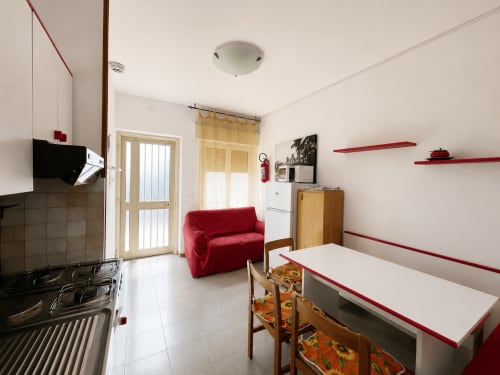 Paluzza Apartment in Lignano Sabbiadoro with kitchen, red sofa, dining area, and modern amenities