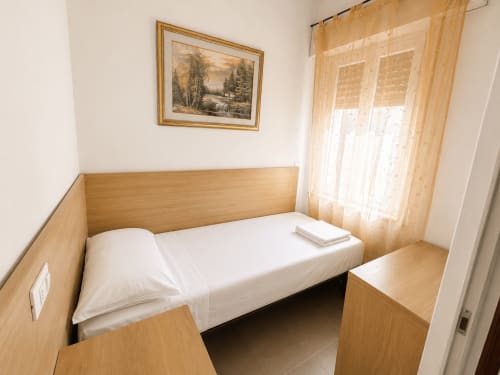 Compact bedroom in Paluzza Apartment at Anthea Hotel, Lignano Sabbiadoro, with single bed, wooden furniture, and sheer