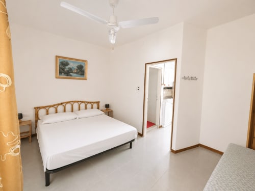 Anthea hotel bedroom in Lignano Sabbiadoro with double bed, wooden frame, white ceiling fan, and en-suite bathroom