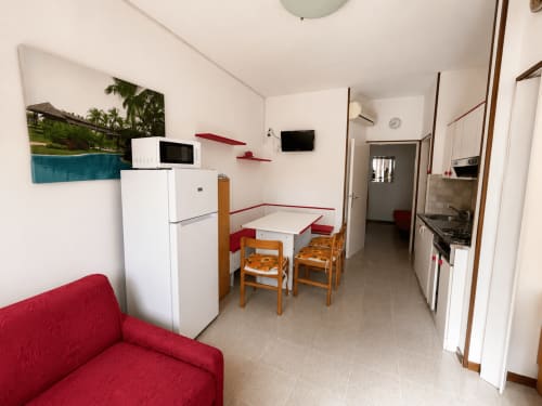 Anthea hotel Paluzza apartment in Lignano Sabbiadoro with red sofa, white kitchen, dining table and modern amenities