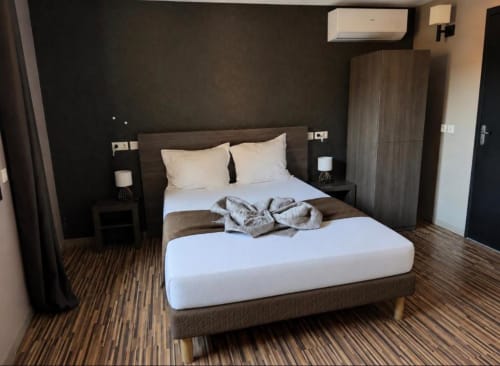 Chambre double accessible et moderne à l'Hôtel de la Bourse avec literie blanche, mobilier en bois foncé et sol à rayures
