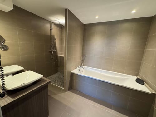 Modern bathroom in Deluxe Room at Hôtel de la Bourse with walk-in shower, bathtub, and double vanity sink, Bagnols-sur-Cèze
