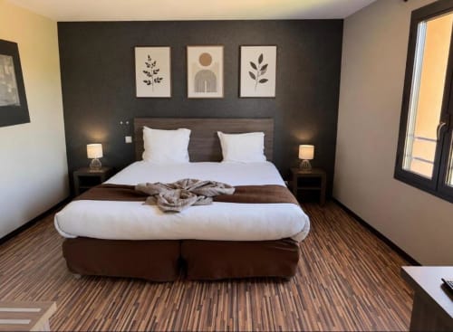 Deluxe double bedroom at Hôtel de la Bourse in Bagnols-sur-Cèze with dark accent wall, white bedding, and modern decor.