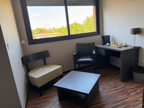 Deluxe hotel room at Hôtel de la Bourse with black furniture, work desk, seating area, and city view windows in