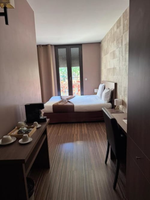 Modern double bedroom at Hôtel de la Bourse in Bagnols-sur-Cèze with city view balcony, flat-screen TV, and contemporary