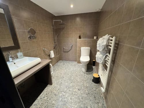 Accessible bathroom at Hôtel de la Bourse in Bagnols-sur-Cèze with walk-in shower, white sink, toilet, and heated towel rack.