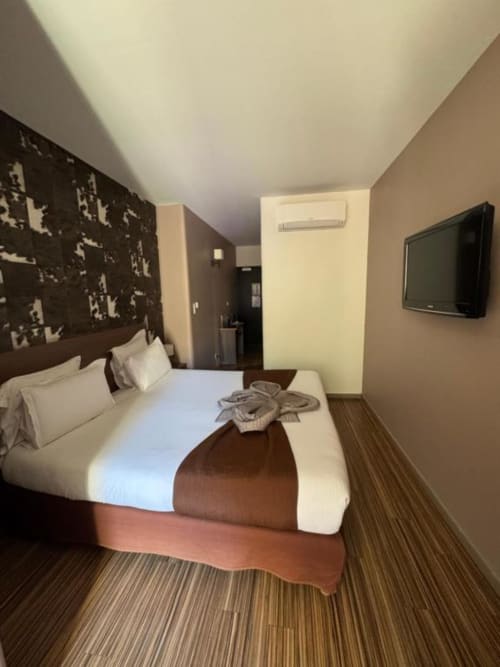 Modern double bedroom at Hôtel de la Bourse in Bagnols-sur-Cèze with flat-screen TV, air conditioning, and city view