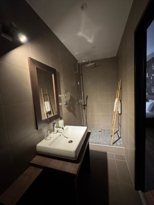 Modern bathroom in Room 2 at Hôtel de la Bourse, Bagnols-sur-Cèze with white sink, shower, mirrors and tiled walls