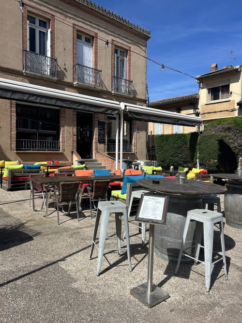 Terrasse extérieure de l'hôtel BDM avec sièges colorés et tables de bar à Montastruc-la-Conseillère