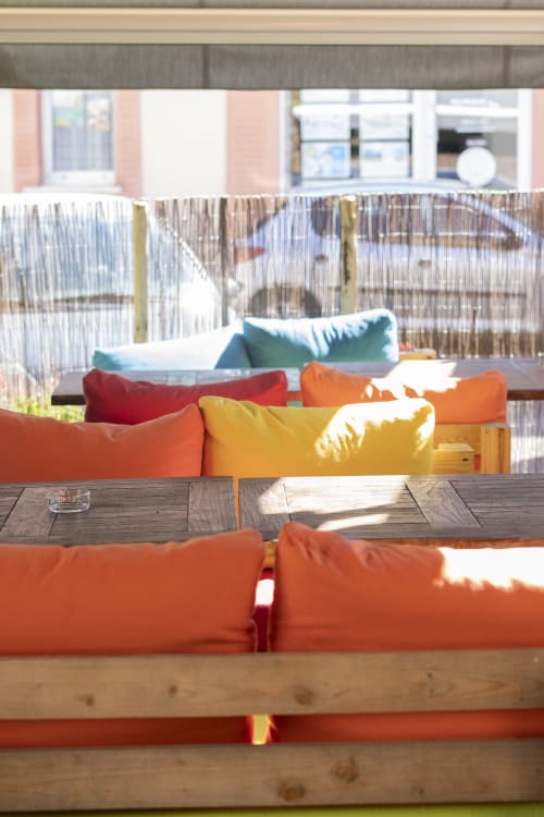 Espace de détente coloré à l'hôtel BDM avec coussins vibrants et tables en bois surplombant Montastruc-la-Conseillère