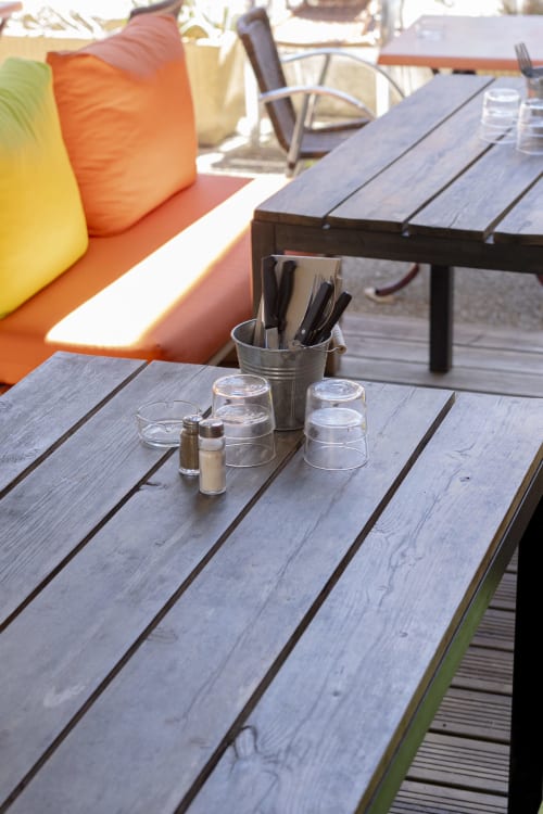 Table de salle à manger en terrasse au BDM Hotel avec condiments et couverts, sièges colorés et rembourrés à proximité