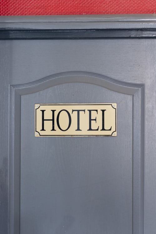 Enseigne d'hôtel sur une porte cintrée grise avec mur rouge à l'Hôtel BDM à Montastruc-la-Conseillère