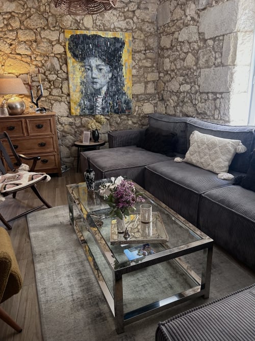 Élégant salon de La Maison du Clocher à Saint-Emilion : murs en pierre, canapé anthracite et art contemporain