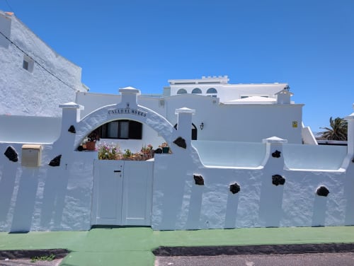 Villa de paredes blancas con entrada arqueada y macetas de flores, Finca Villanueva Lanzarote en Mala, Islas Canarias