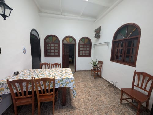 Comedor de la villa Finca Villanueva en Lanzarote con sillas de madera, mantel colorido, ventanas de arco y azulejos de barro cocido